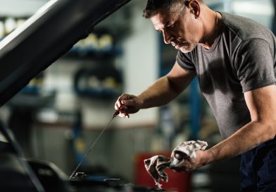 Mecanic verificând nivelul uleiului de motor cu joja, într-un service auto