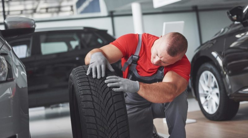 Mecanic verificând o anvelopă auto.
